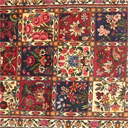 Central Persian Bakhtiar hand-knotted runner, field arranged with a garden panel  design of floral sprays and foliage within a flowerhead and vine border, in tones of crimson, ivory, and indigo with cotton fringe ends 