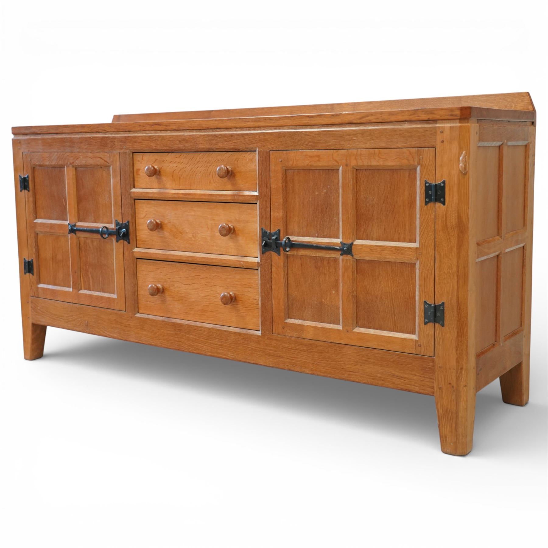 Rabbitman - oak sideboard adzed top with galleried top, with three graduating drawers to the centre, flanked by two panelled and lightly adzed doors, iron latches and hinges, raised on tapered stile supports, with carved rabbit signature, by Peter Heap of Wetwang   