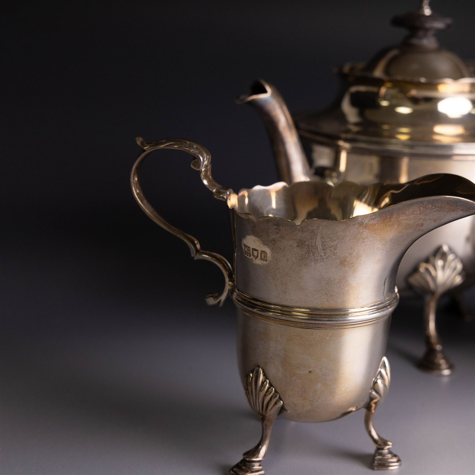Early 20th century silver three piece bachelor's tea service, comprising teapot, open sucrier and milk jug, all of circular waisted form with shaped rims and upon three stepped feet, the teapot with ebonised wooden handle and finial, hallmarked Wakely & Wheeler, London 1914, teapot height H15cm