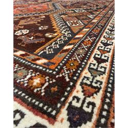 Southwestern Persian Qashqai hand-knotted carpet, the field with a lattice of hexagonal medallions in rust, indigo, and ochre, each containing stylised tree and floral motifs, flanked by lozenge panels with geometric designs, enclosed by multiple borders with rosettes and leaf motifs