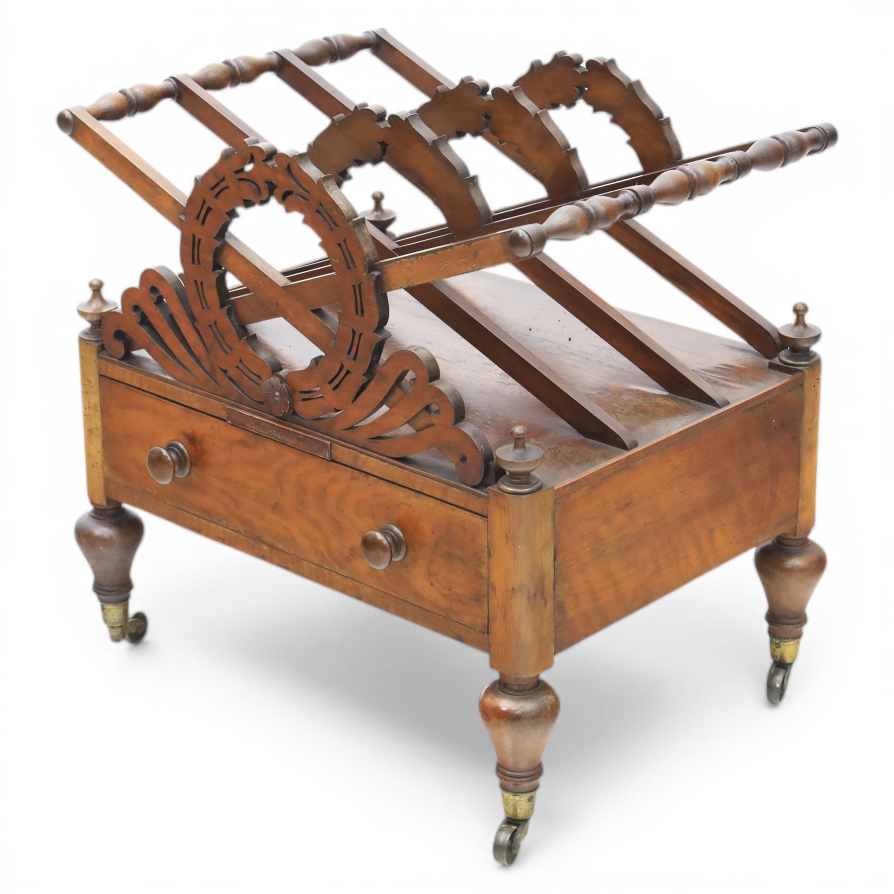 19th century mahogany music canterbury, with pierced dividers united by turned handles, above a single frieze drawer, raised upon baluster supports on brass castors