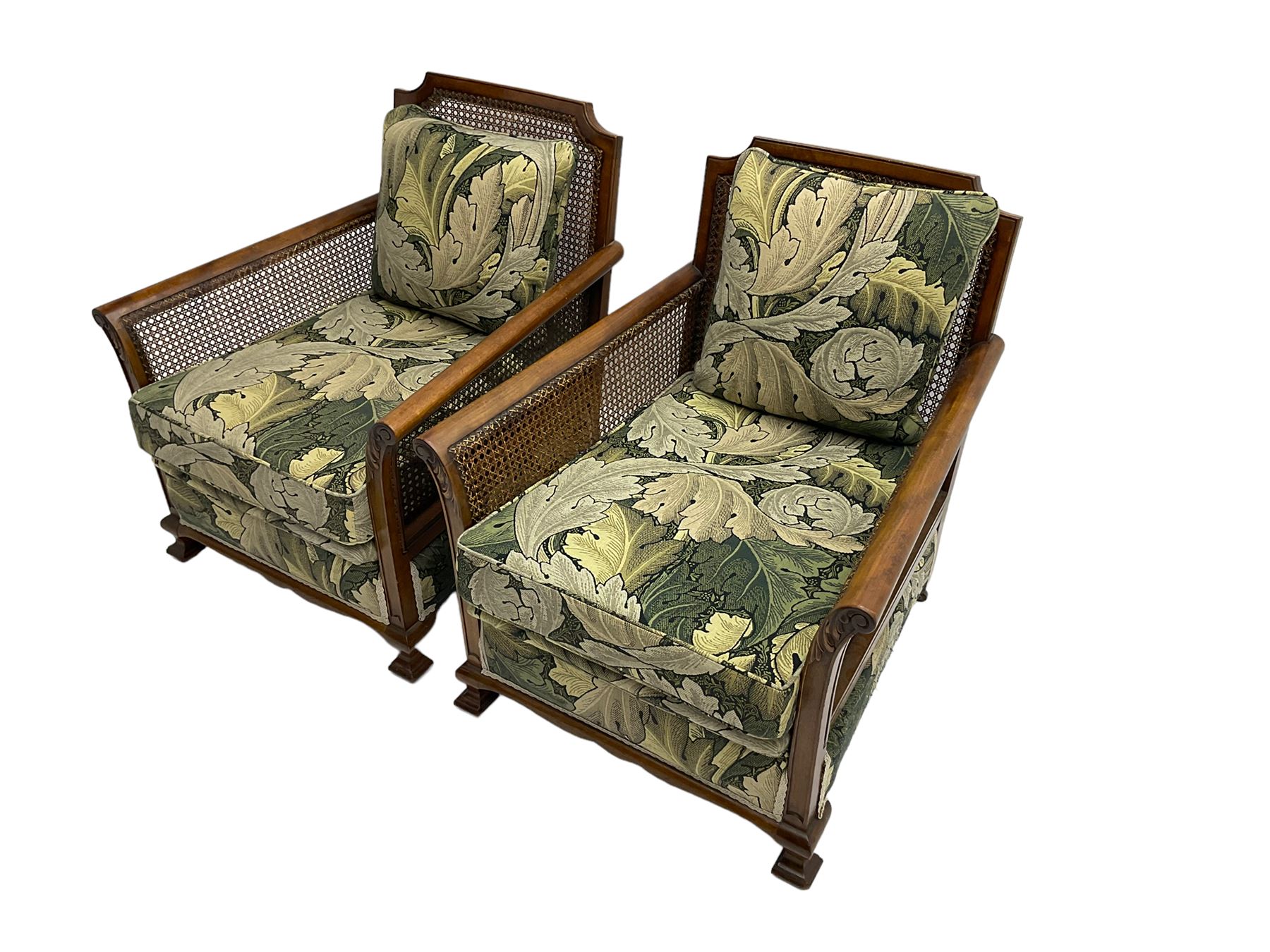 Early 20th century bergère lounge suite, mahogany framed with cane work back and sides, acanthus scroll carved uprights - three seat sofa (W167cm, H82cm, D83cm), and pair matching armchairs (W78cm), loose cushions upholstered in acanthus leaf scroll fabric with scatter cushions