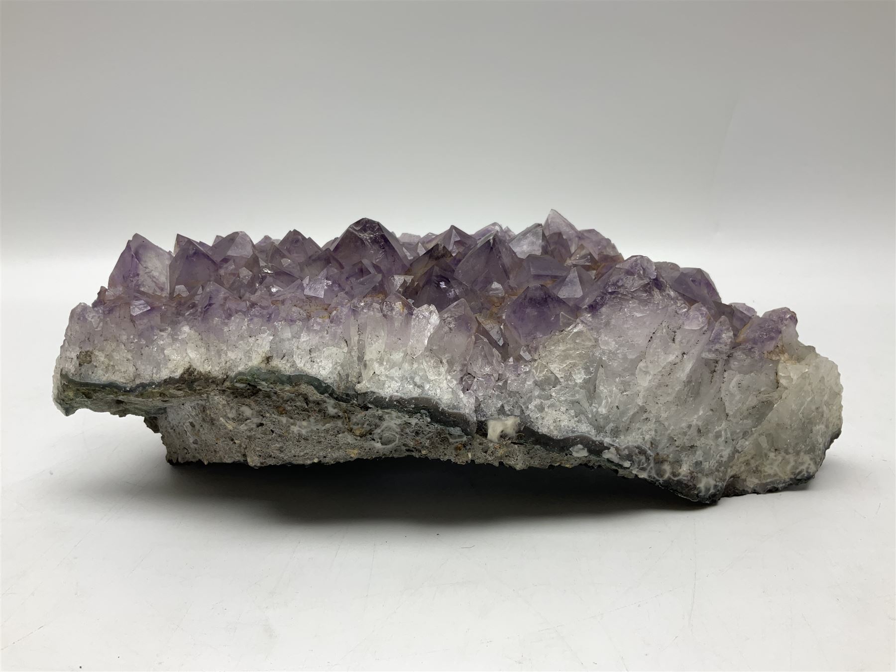 Amethyst crystal geode cluster, with well-defined crystals of various sizes, H10cm, L30cm