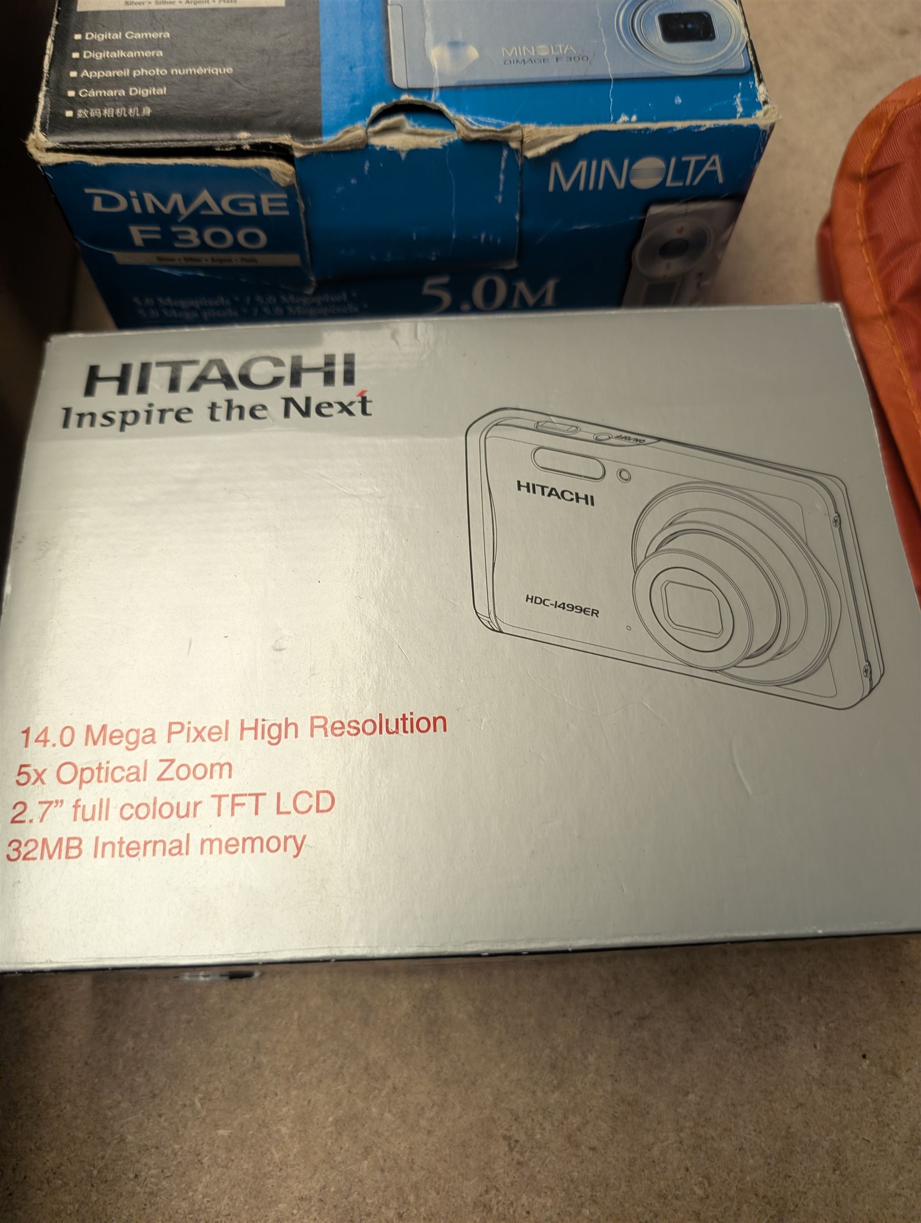 Minolta Dimage F300 digital camera and a Hitachi HDC-1499 digital camera, both boxed, together with a collection of camera accessories including filters, straps and cases 