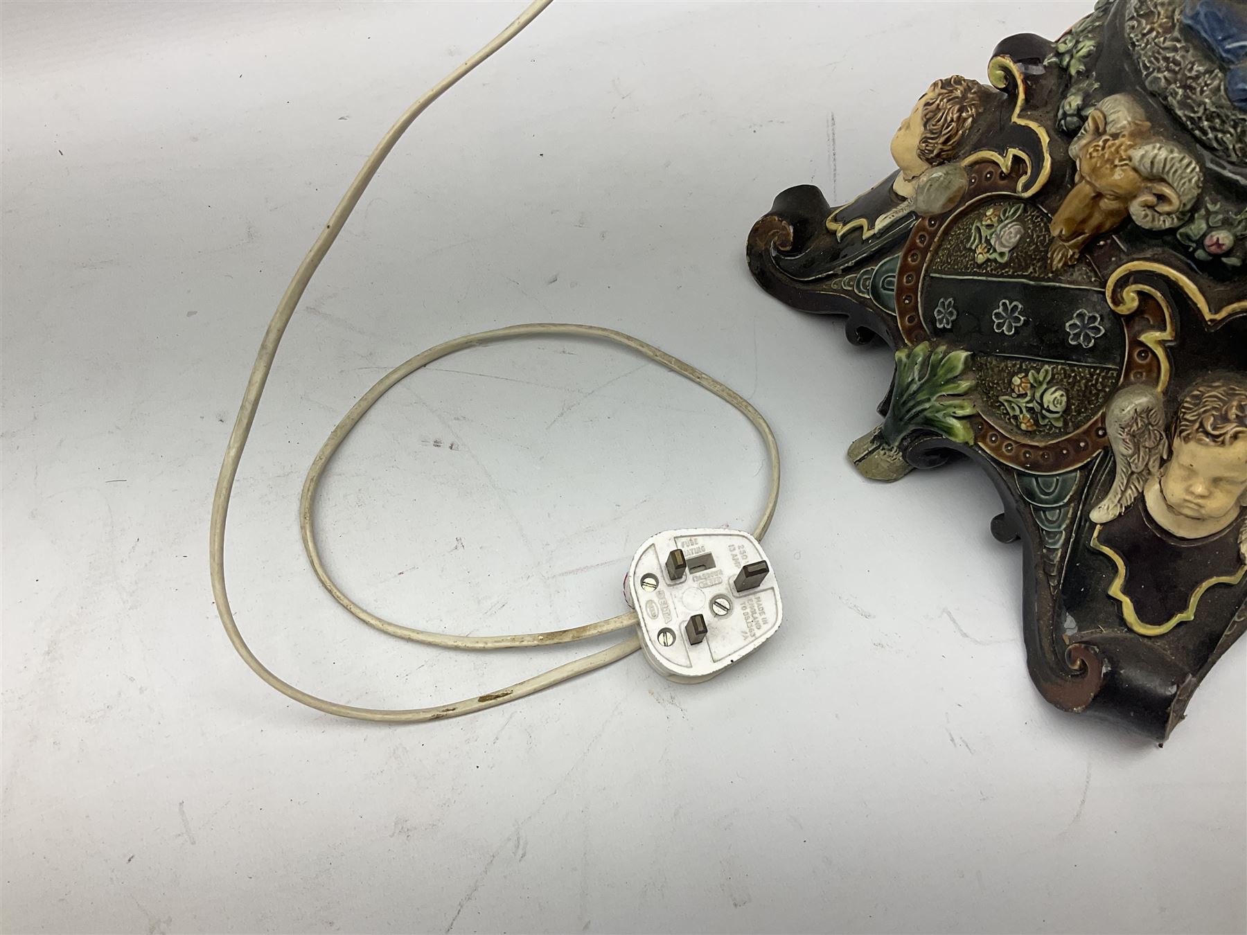 Composite table lamp modelled as a Roman Emperor donning blue robes, upon quatrefoil base modelled with rams heads and winged cherubs, H56cm excl fitting