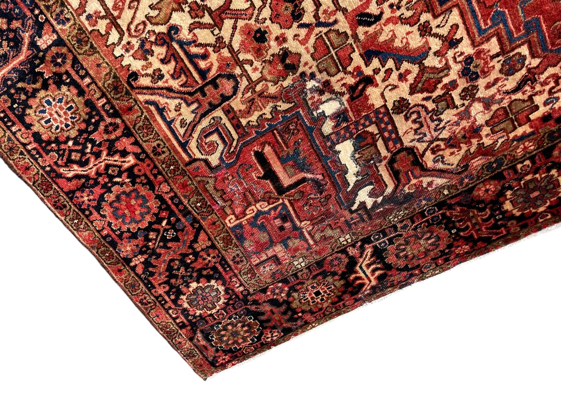 Persian Heriz red ground carpet, large stylised pole medallion surrounded by Pitrak motifs, indigo ground border decorated with stylised flower heads and trailing leafy branches, within floral pattern guard stripes