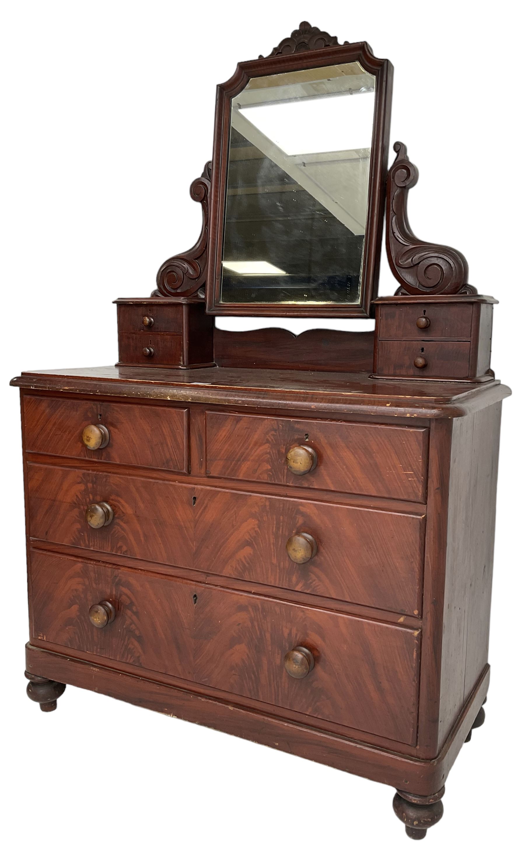 Victorian scumbled pine dressing chest, raised swing mirror in moulded frame with scrolled carved pediment, foliage S-scroll carved supports over trinket drawers, moulded rectangular top with rounded corners over two short and two long drawers, skirted base on turned feet, scumbled to resemble mahogany 