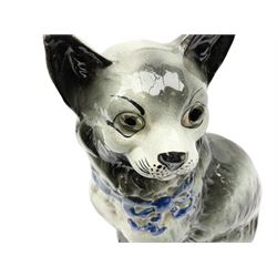 Staffordshire model of a seated cat, with blue bow detail around neck and inset glass eyes, H30.5cm