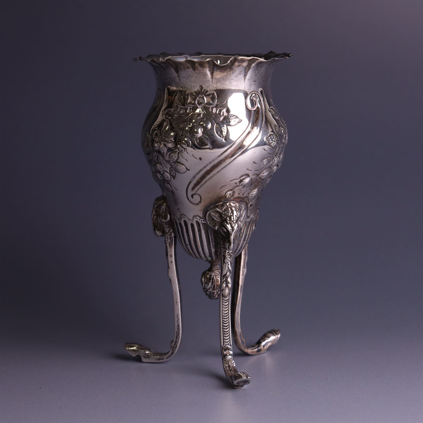 Late Victorian silver vase, of baluster form with fluted rim, the body with embossed floral decoration, upon three tall legs with ramshead mounts, hallmarked William Comyns & Sons, London 1890, H13.5cm