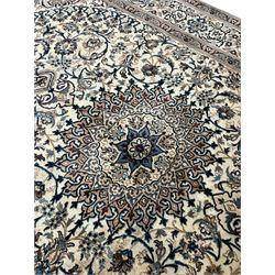 Persian Kashan ivory ground carpet, central rosette medallion surrounded by swirling leafy branches and floral sprays, the main border with scrolling pattern interspersed with floral motifs, within guard stripes 