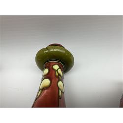 Minton Secessionist vase, with tube-lined stylised flower head decoration upon a red and green ground, printed mark to base 'Minton Ltd, No. 31', together with a matching pair of Minton Secessionist candle sticks, candlestick H17cm