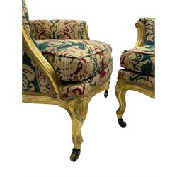 William Bertram & Son of London - pair late 19th century giltwood armchairs, moulded frame with scroll carved back and arm terminals, upholstered in striped fabric with foliate pattern, on shell carved cabriole supports, the brass castors stamped 