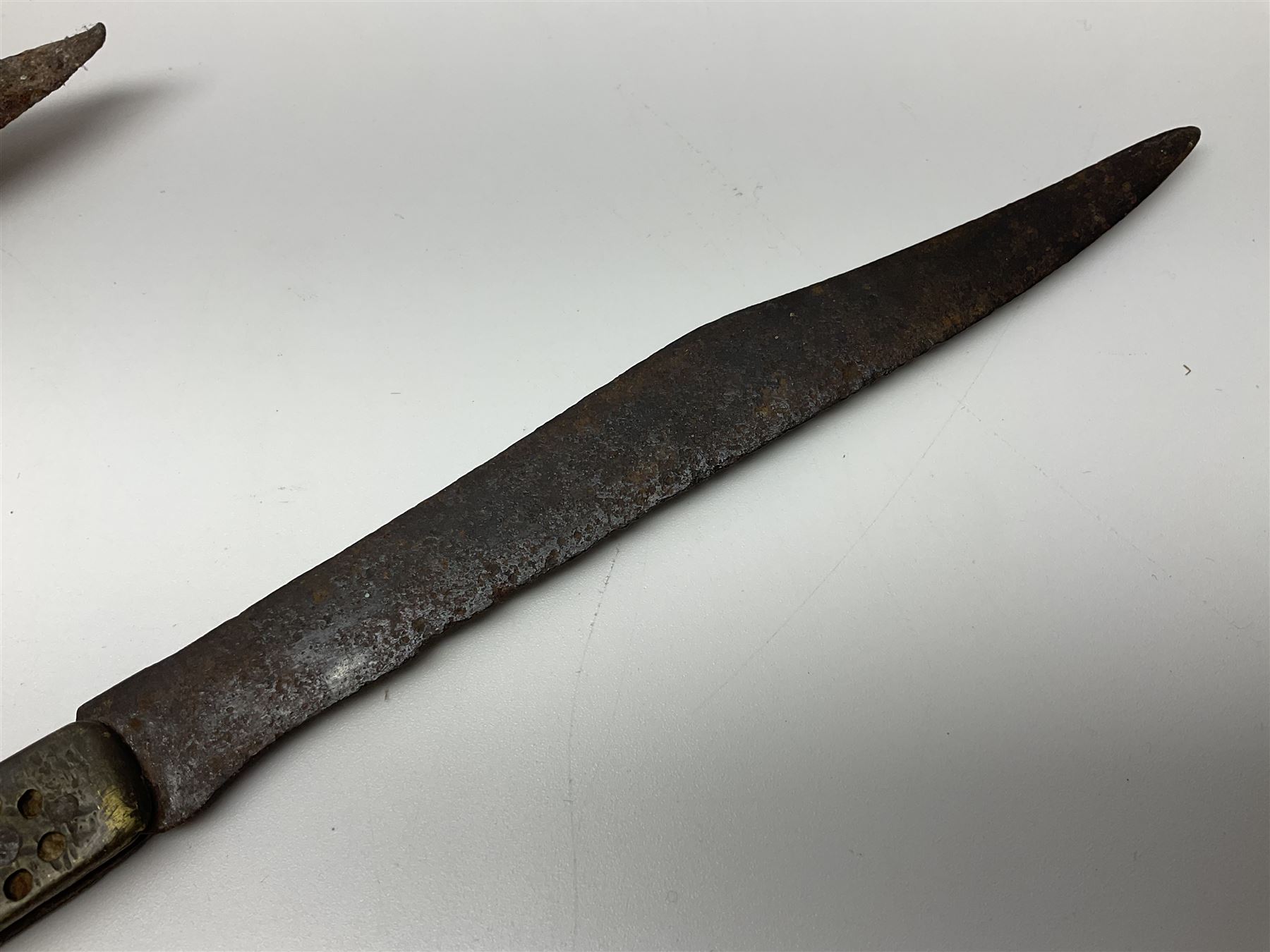 19th century continental folding knife with 15.5cm single edged blade, the pierced brass and iron handle with remains of horn grips L21.5cm overall closed; turned horn handled knife with foliate engraved blade; battlefield relic German 1884/98 knife bayonet; iron spear head; leather covered swagger stick; and two-piece gun cleaning rod