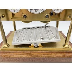 Mid 20th century 'Congreve' rolling ball clock, sloped arch and pierced brass movement, the central Arabic minute chapter ring flanked by hour and seconds dials, twin train driven eight day movement, raised on mahogany plinth with turned brass feet, under acrylic cover