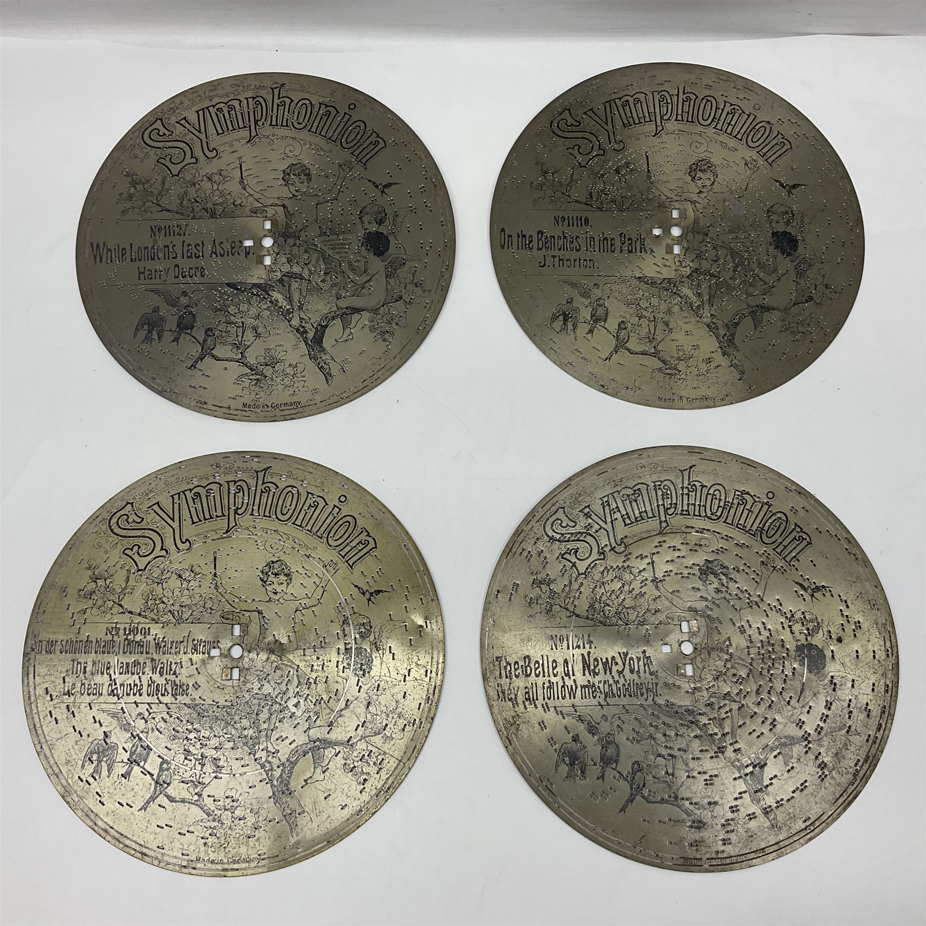 Late 19th century Symphonion disc musical box for spares or repair, inlaid walnut case with front lever action, playing 25.5cm discs on a 10.5cm steel comb with forty-nine teeth, musical scene of cherubs under the lid, L33cm; together with twelve 25.5cm discs