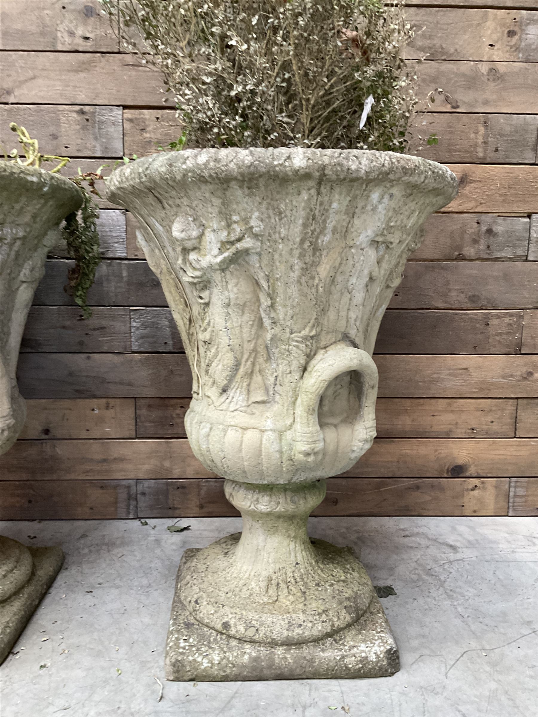 Set of four Victorian design cast stone Grecian urns, tapering form cast with figures and handles, square plinth bases