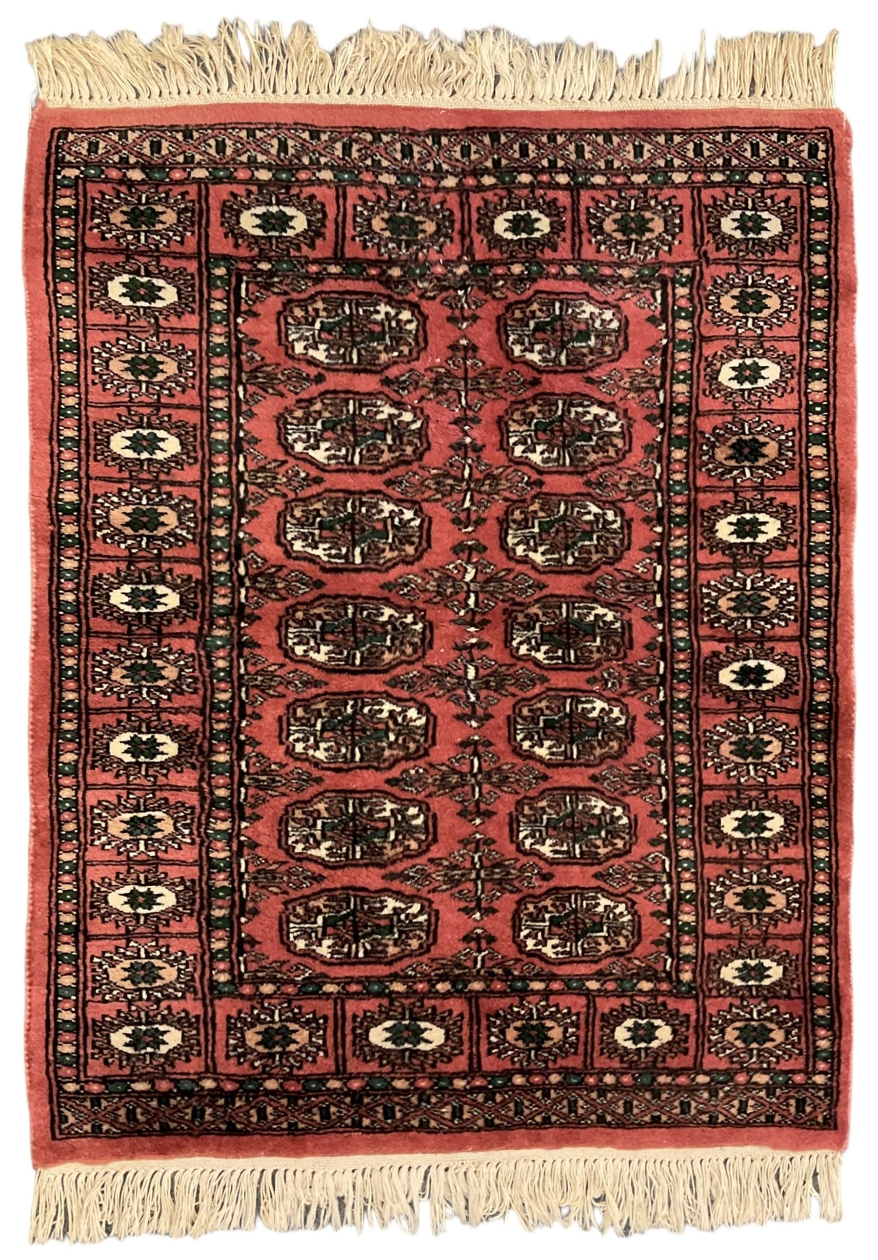 Small peach ground Bokhara rug, decorated with two rows of Gul motifs 
