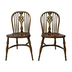 Set of four elm Windsor dining chairs, high hoop and stick back with shaped pierced splat, over shaped saddle seat, raised on ring turned supports joined by crinoline stretcher