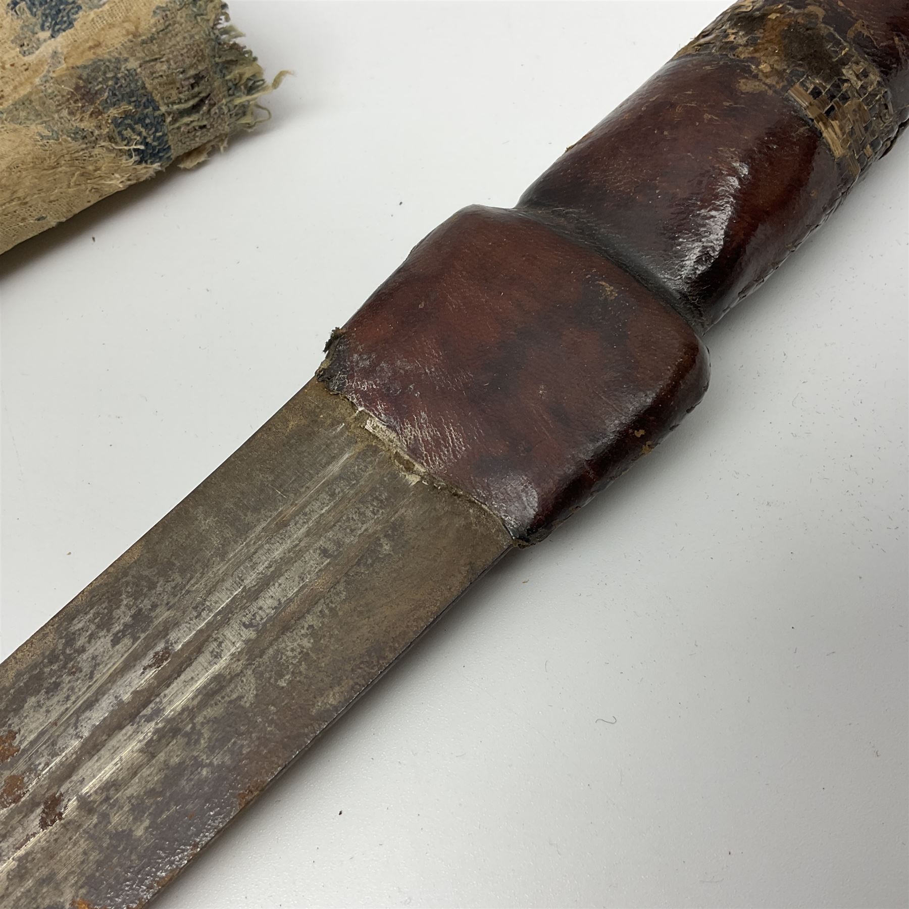 African Mandingo sword, the 75cm triple fullered blade with leather covered grip and brass pommel, in part leather covered scabbard with leaf shaped point L98cm overall