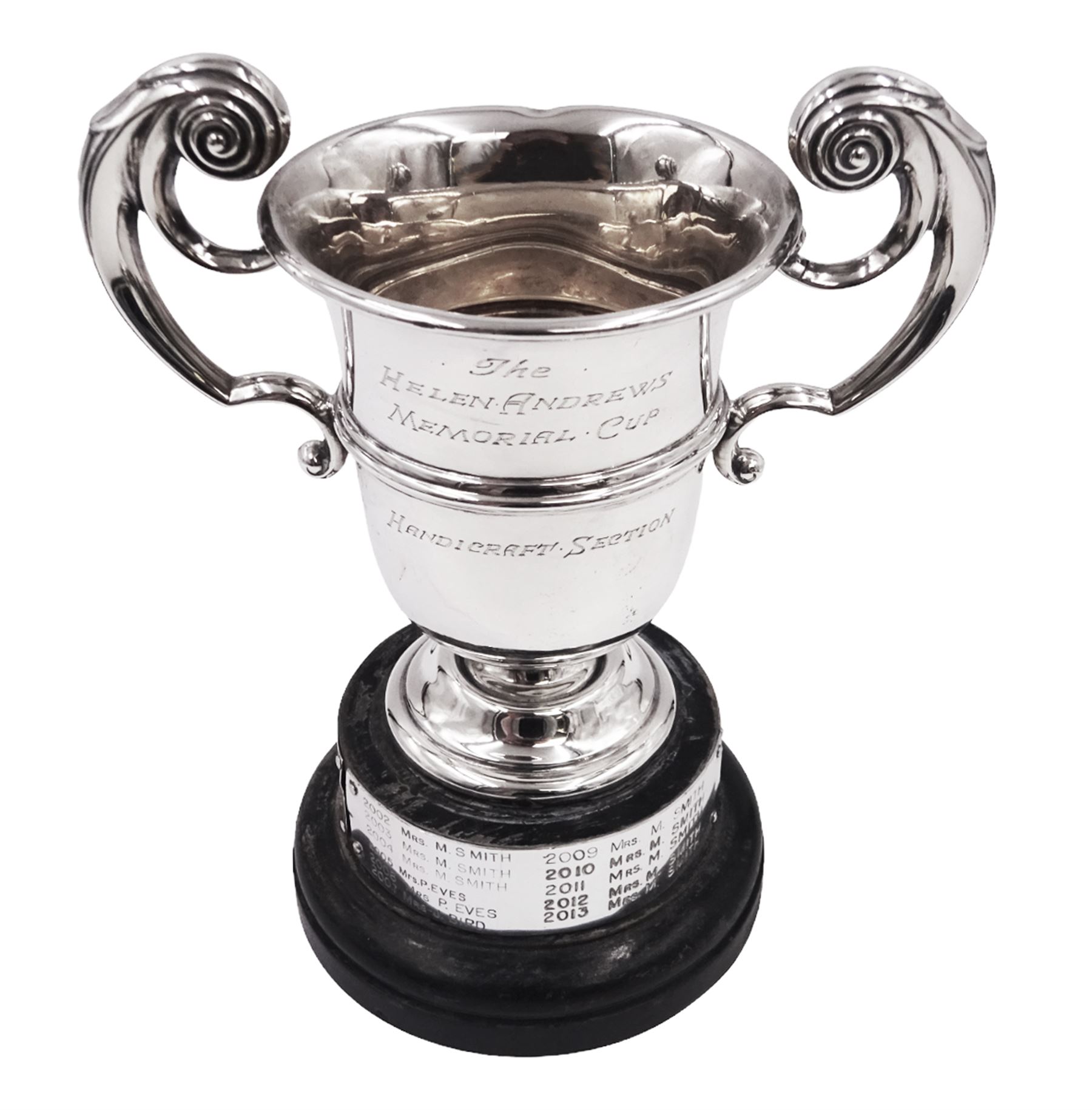 1920s silver trophy cup, with twin scroll handles and girdle, upon circular stepped foot,  the body with presentation engraving 'The Helen Andrews Memorial Cup, Handicraft Section', hallmarked Walker & Hall 1927, fixed upon ebonised wooden base with applied winners plaques, including base H18cm