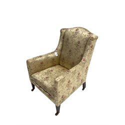 Late 19th century mahogany framed wingback armchair, upholstered in champagne floral patterned fabric with sprung seat, raised on square tapering supports with ceramic castors