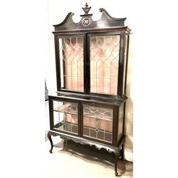 Late 19th century mahogany Empire style display cabinet, swan neck pediment and carved urn finial over two lead glazed doors enclosing two shelves, two glazed doors under, raised on cabriole front supports