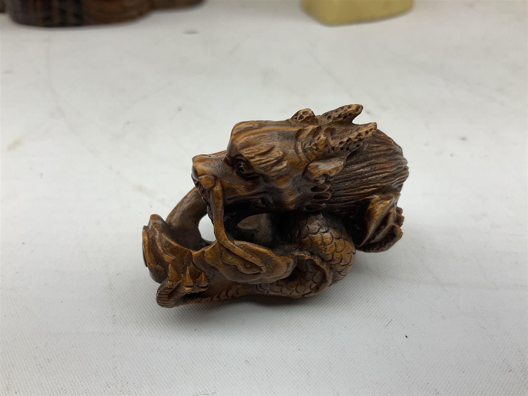 Hardwood bust of an Indoniesian Goddess, carved wearing a pierced headdress, from Klungkung, Bali, H20cm, together with a pair of bone carvings of deity figures, and a carved wood Netsuke in the form of a Chinese dragon