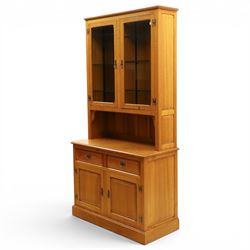 Knightman - oak dresser, the upper section fitted with twin glazed doors enclosing glass shelves, over open recess with panelled back, the base fitted with two drawers over twin panelled cupboards enclosing shelves, with recessed carved knight trademark, by Horace Knight of Old Mill Furniture, Balk near Thirsk