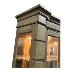 Brunswick - washed oak finish illuminated display cabinet, upper section with four glass-panelled doors enclosing glass shelving, base fitted with two drawers over four paneled cupboard doors, each fitted with distinctive round metal handles, raised on plinth base