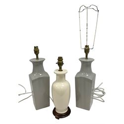 Pair of grey ceramic table lamps, together with another lamp on a wooden plinth