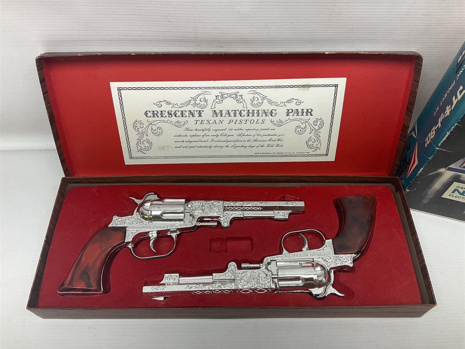 Crescent, Cap Guns - boxed 'Crescent Matching Pair' of 'Texan Pistols' toy cap guns; containing two ''Rustler Texan' ornately decorated pistols finished in silver / plated effect with brown marbled moulded grips; and Japanese Gakken Electronic Project Kit; boxed with wooden base and instruction booklet (2)