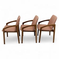 Mid-20th century Danish teak armchairs, each with curved open arms and upholstered seat and backrest in salmon pink striped fabric, raised on tapering legs