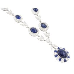 18ct white gold sapphire and diamond milgrain set necklace, oval cabochon cut sapphire surrounded by eight round brilliant cut diamonds and eight French cut sapphires, suspending from a diamond set leaf pendant, single round brilliant cut diamond and a larger old cut diamond, the chain set with six graduating cabochon cut sapphires, each surrounded by diamonds and spaced by a single diamond and a diamond set leaf, to a belcher link chain necklace, hallmarked, total sapphire weight approx 27.00 carat, total diamond weight approx 7.50 carat