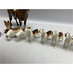 Beswick hunting group, comprising huntswoman on grey horse no 1730, huntsman on brown horse no 1501, two seated fox figures no 1748 and seven fox hounds, all with printed marks beneath (11)