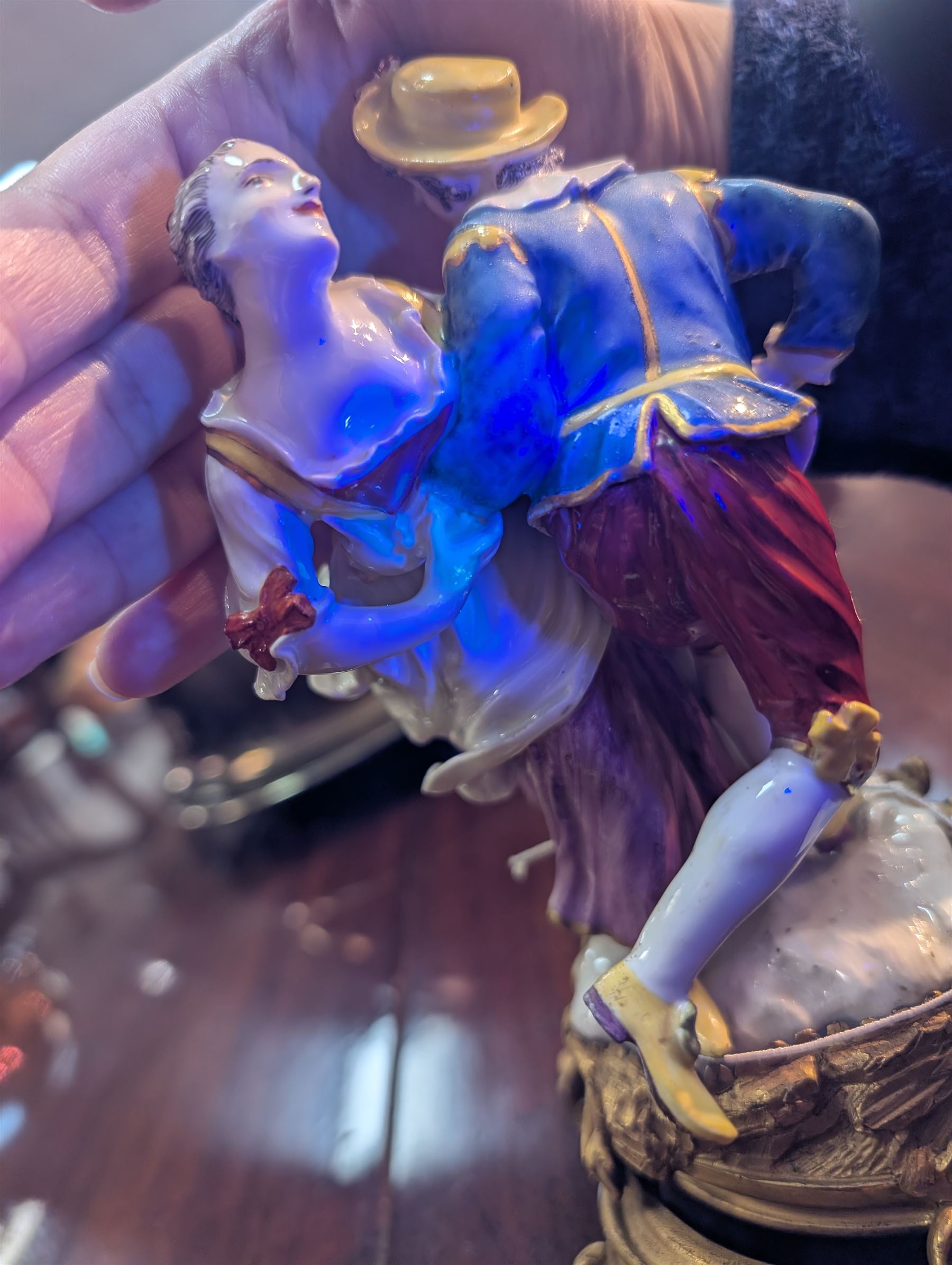 Mid 18th century Meissen figure group, The Tyrolean Dancers, circa 1740, modelled as two swirling figures with their arms linked, he in yellow hat with red rosette, blue jacket, red breeches with red rosette, and yellow shoes with green rosette, she in white blouse with red ribbons, yellow and red bodice, white apron over puce skirt and yellow shoes with green rosettes, her hair fashioned into two plaits secured by red ribbon, upon a shaped mound base, within a scrolling gilt metal mount, with blue crossed swords mark to base, overall H19cm
