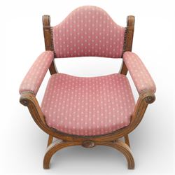 Late Victorian oak x-frame armchair, upholstered padded back and seat covered in pink patterned fabric with close studded borders, shaped downswept arms with scroll terminals, raised on curved x-frame supports with moulded scroll feet