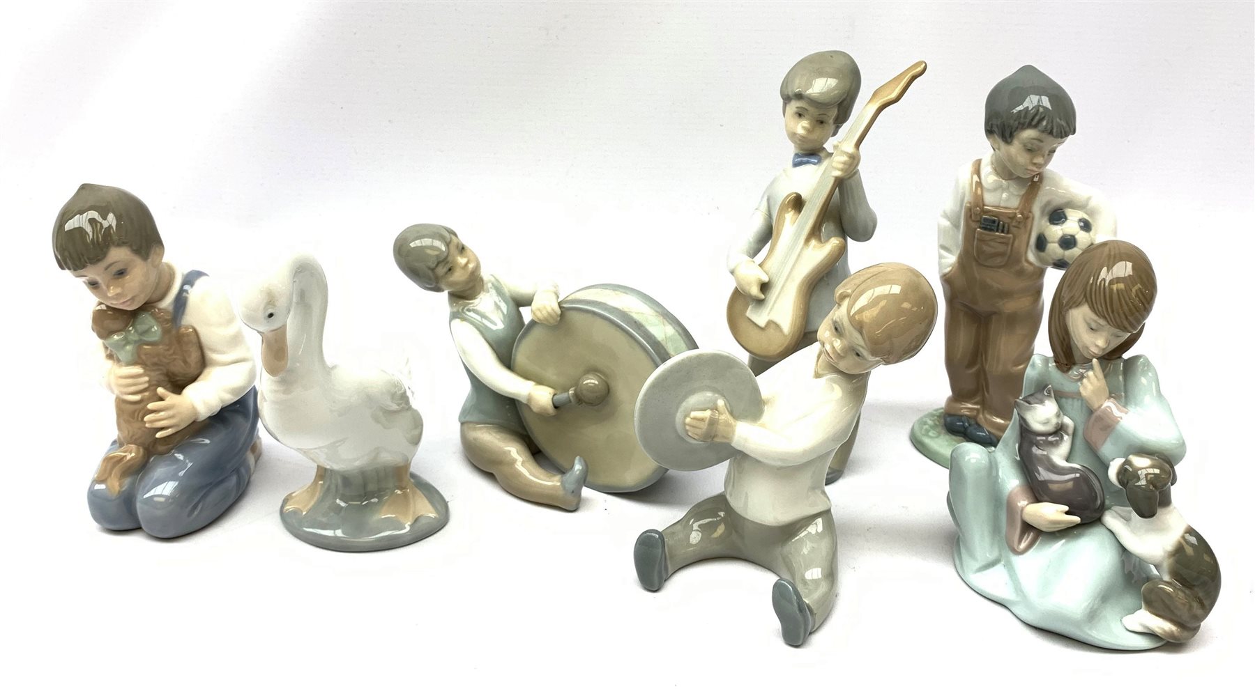  A group of Lladro and Nao figurines, comprising a trio modelled as boys playing instruments, boy with dog, boy with football, girl with puppy and kitten and a goose, (two a/f), all with printed mark beneath.   
