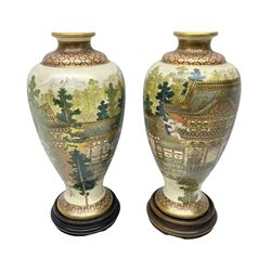 Pair of Japanese Satsuma vases, decorated with temple within a landscape, upon wooden stands, H22cm