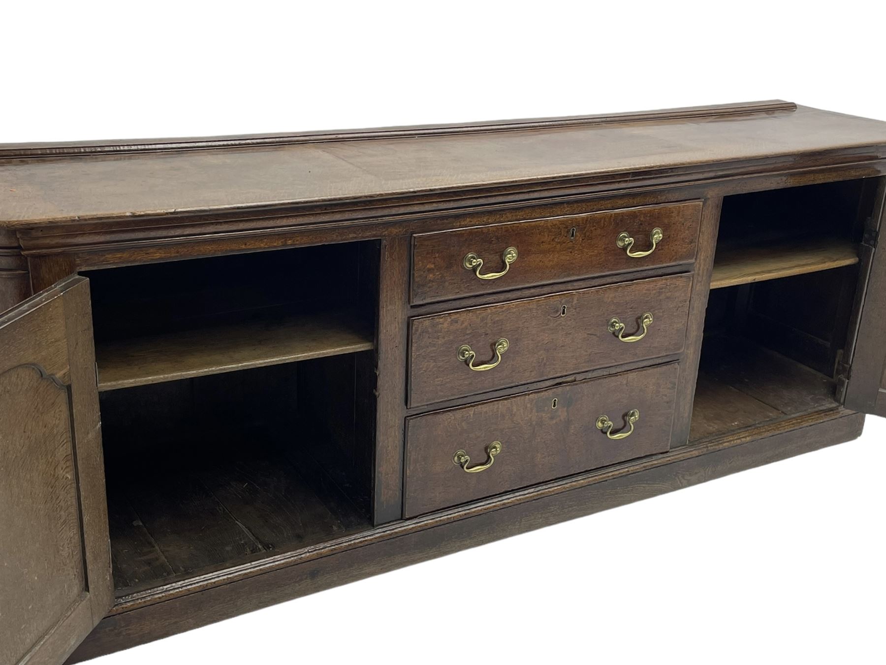 George III oak dresser base, rectangular top with rounded corners over moulded frieze rail, canted corners with turned quarter columns, fitted with three drawers with moulded edges flanked by two cupboards, enclosed by ogee arched fielded panelled doors, panelled sides, moulded plinth base