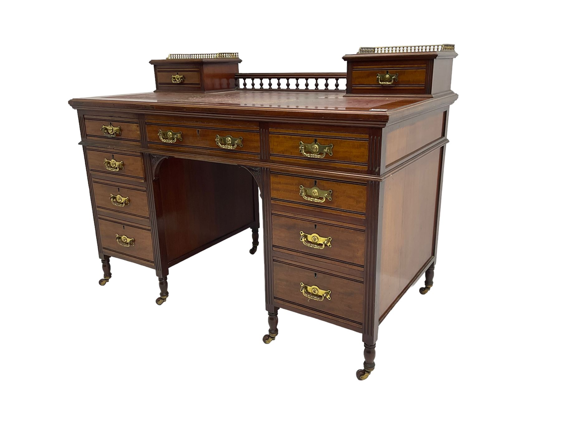 Maple & Co - Edwardian mahogany twin pedestal desk, the raised back with spindle gallery and open shelf to centre flanked by two trinket drawers, rectangular top with inset writing surface, fitted with one long and eight short graduating drawers flanked by fluted uprights, raised on brass and ceramic castors, stamped to central drawer