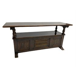 Jacobean design oak Monks bench, the front with carved linenfold panels, hinged metaphoric table back, hinged box seat compartment, on sledge feet