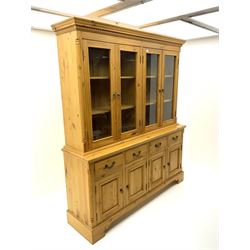 Pine Welsh dresser, projecting cornice above four glazed cupboard doors enclosing fitted shelving, base unit fitted with four short drawers above four panelled cupboards, raised on plinth base