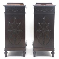 Pair early 20th century Hepplewhite style mahogany pedestal cabinets, cavetto moulded top with foliate carved edge over secret frieze drawer with applied trailing floral and ribbon decoration, each with button release underneath, oval panelled door with trailing harebell and central flower head motif decoration enclosing shelves, fitted cutlery drawer and lined cellarette drawer, on turned acanthus carved feet
