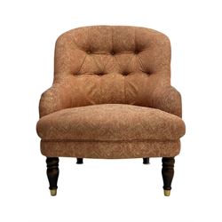 Late Victorian nursing chair, of tub form with deep buttoned backrest, upholstered in pink damask fabric with foliate motifs, raised on turned mahogany legs with brass caps