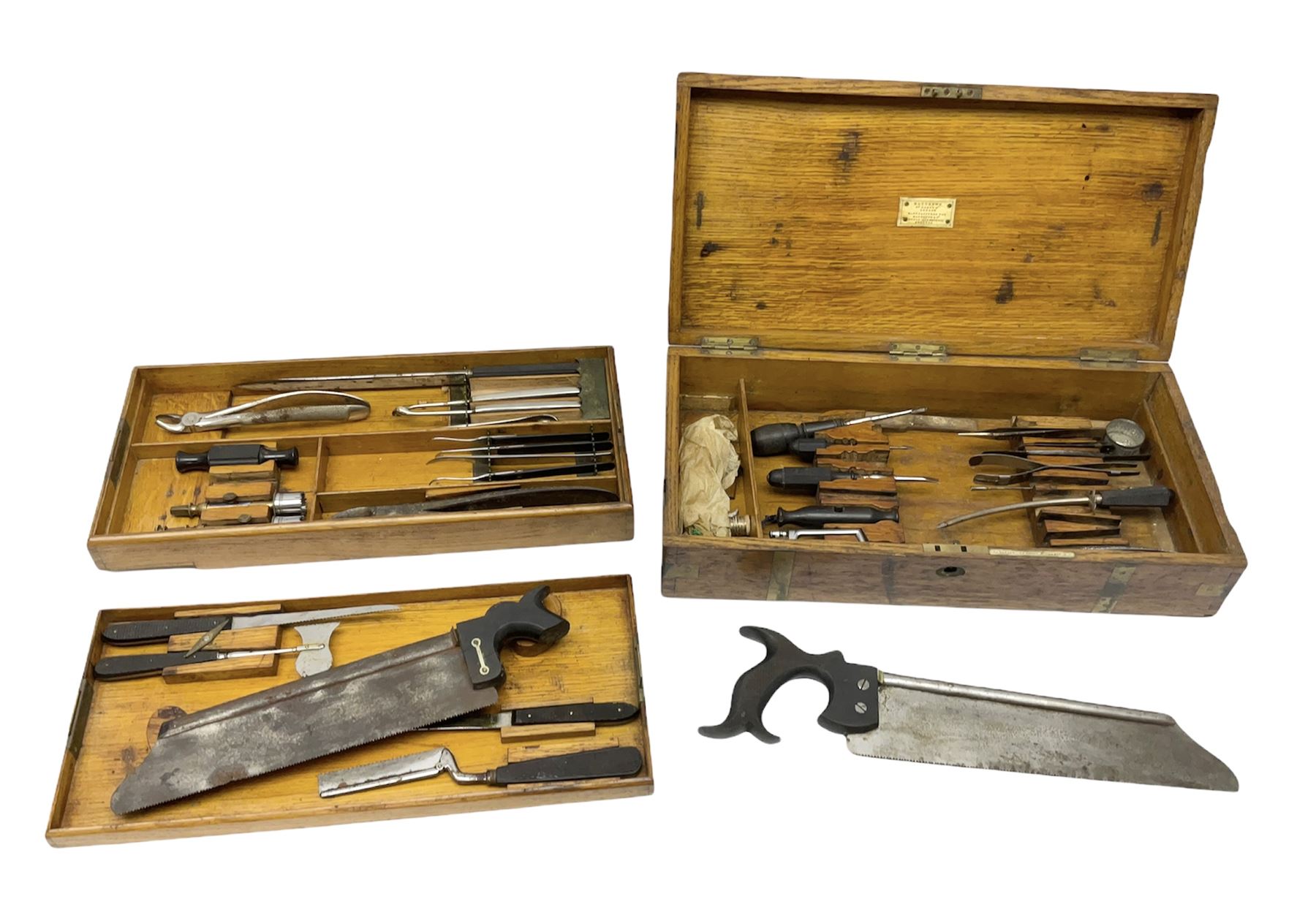 Naval doctor's surgical instruments, contained in a converted brass bound oak pistol box, the hinged lid opening to reveal two removable fitted trays, containing 19th century and later saws, scalpels, tweezers etc