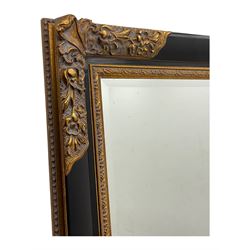 Early 20th century wall-hanging mirror, rectangular bevelled mirror plate within ebonised frame, gilt mounts to the corners carved with floral motifs 
