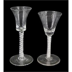 Two 18th century drinking glasses, the first example with bell shaped bowl upon a double series opaque and air twist stem and circular foot, H15.5cm, the second example with funnel bowl upon a double series opaque twist stem and circular foot, H14cm