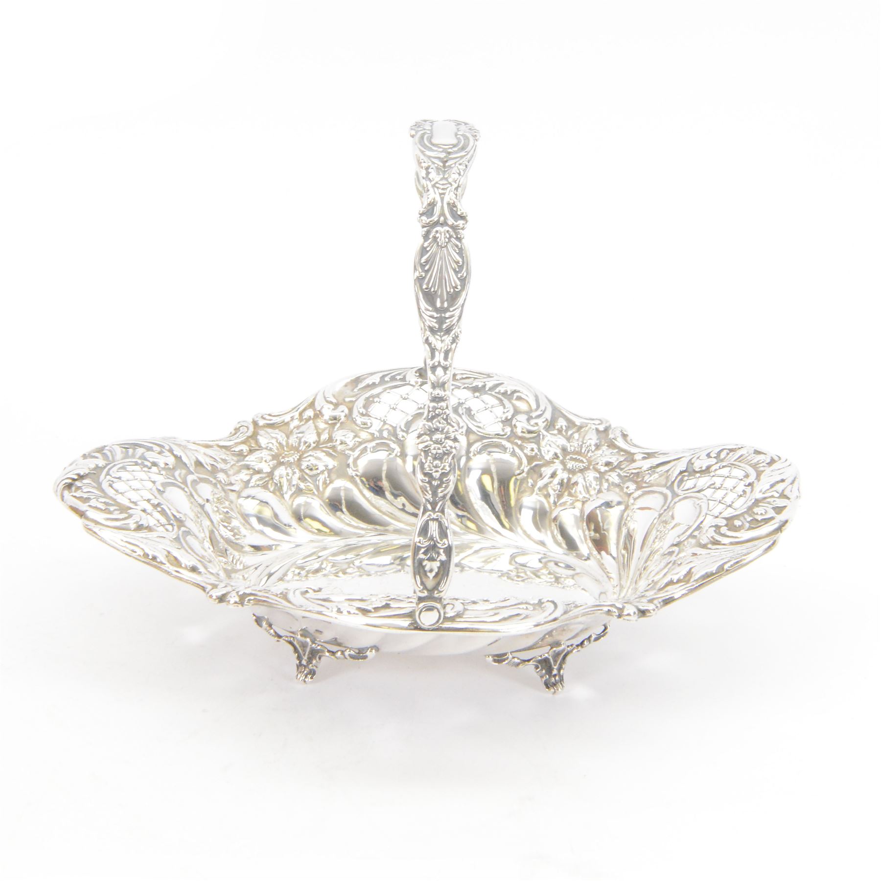 Edwardian silver swing handled basket, of oval form with shaped rim, embossed with floral decoration and with pierced latticework sides, upon four pad feet, hallmarked Chester 1905, maker's mark worn and indistinct