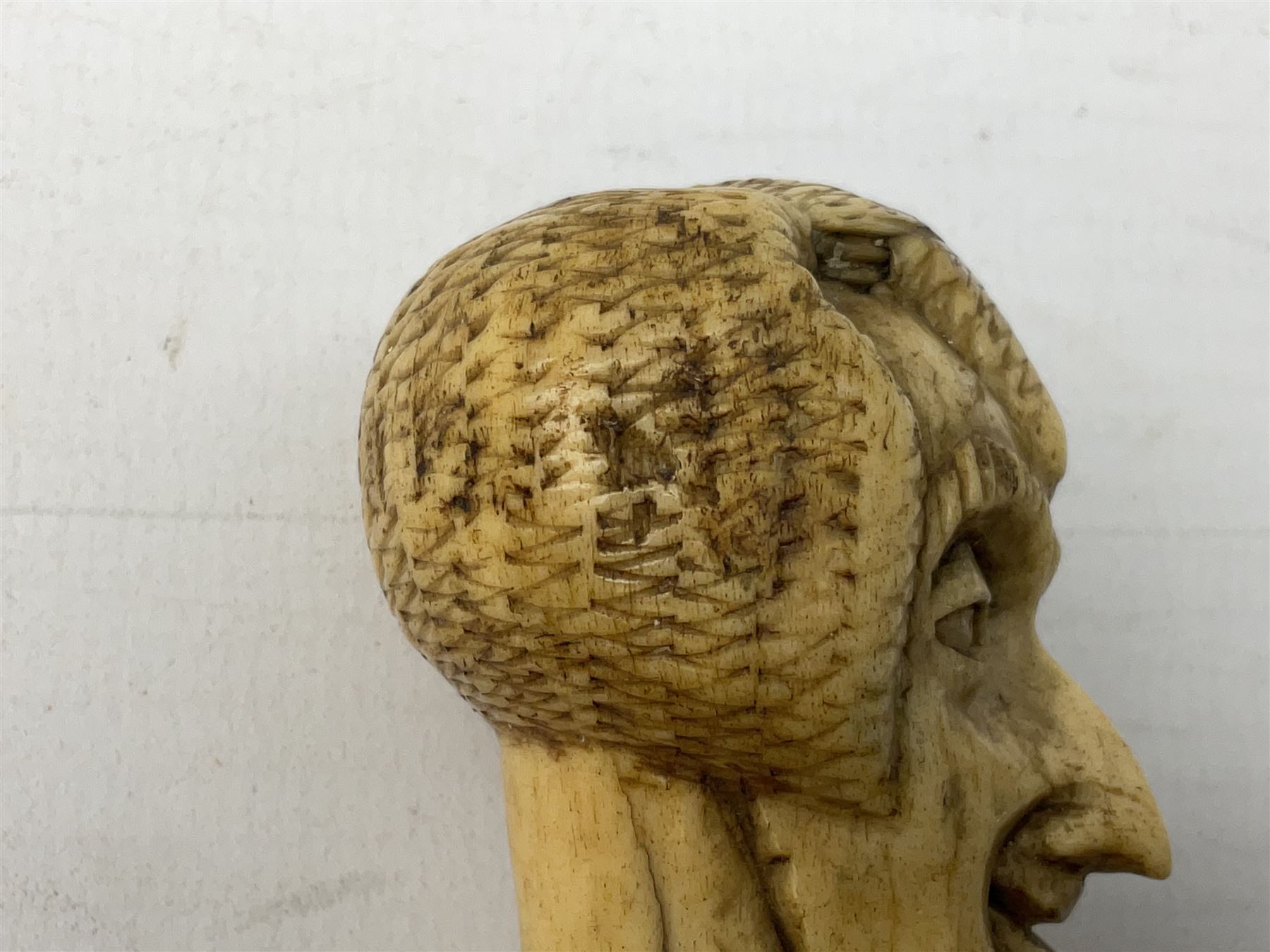 19th century carved ivory walking cane handle, modelled as the head of a greyhound with inset glass eyes, together with a further 19th century ivory example, modelled as a caricature of a gentleman's head, (2)