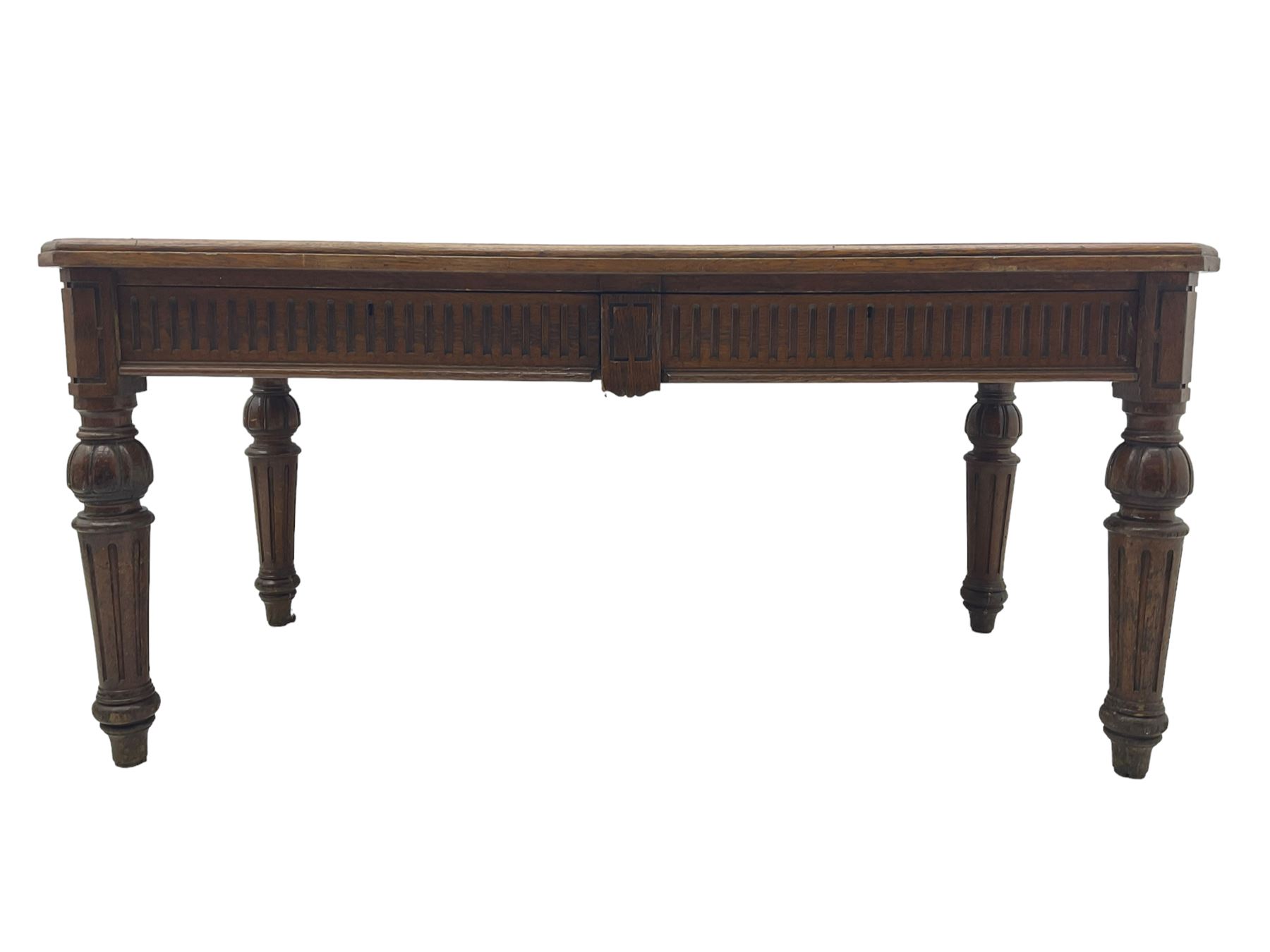 Late 19th century oak library table, moulded rectangular top with canted corners, fitted with two frieze drawers with fluted facias, on lobe carved and fluted turned supports 